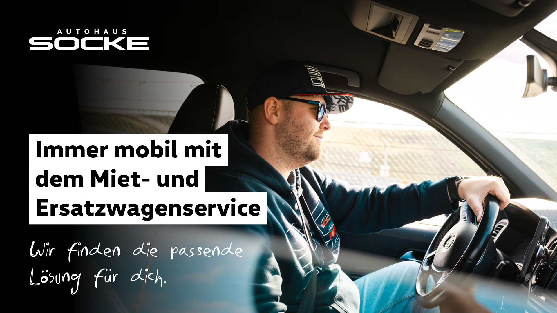 Mann sitzt lächelnd im Auto und fährt einen Mietwagen von Autohaus Socke
