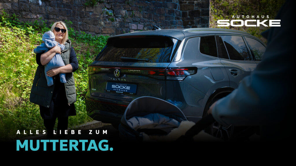 Frau mit Baby auf dem Arm steht neben einem VW Tayron von Autohaus Socke