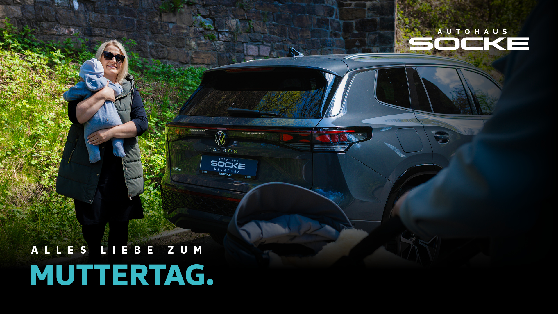 Frau mit Baby auf dem Arm steht neben einem VW Tayron von Autohaus Socke