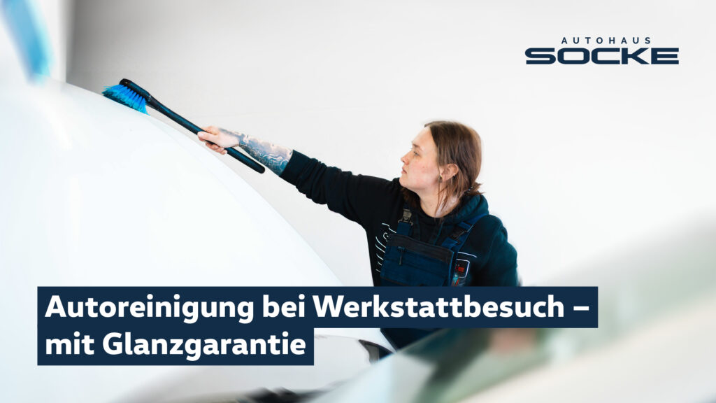 Eine Mitarbeiterin des Autohauses reinigt mit einer Waschbürste die Motorhaube eines weißen Fahrzeugs.
