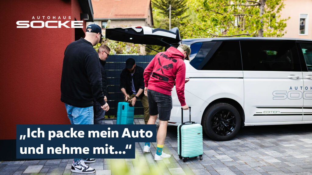 Vier Männer verstauen Koffer in einem Multivan Kofferraum