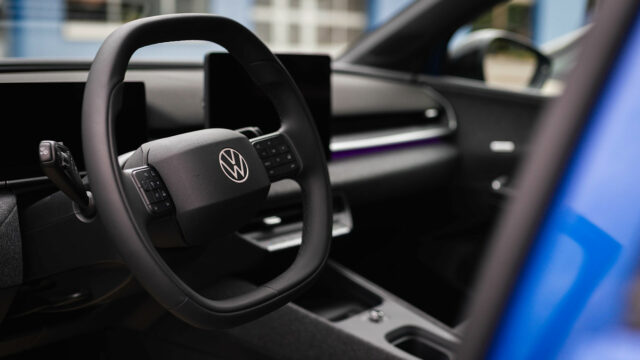 Blick vom Fahrersitz auf das Multifunktionslenkrad mit Volkswagen-Logo, das digitale Instrumentendisplay und den Infotainment-Bildschirm im Cockpit.