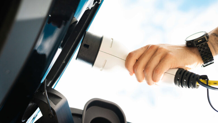 Vogenperspektive auf einen Ladestecker, der in ein E-Auto gesteckt wird